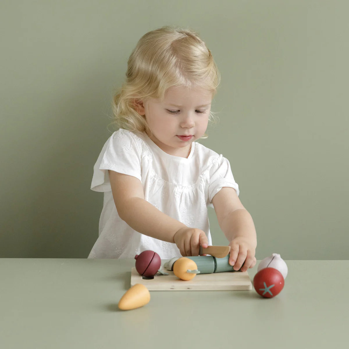 A child playing with the little dutch wooden cutting vegetables