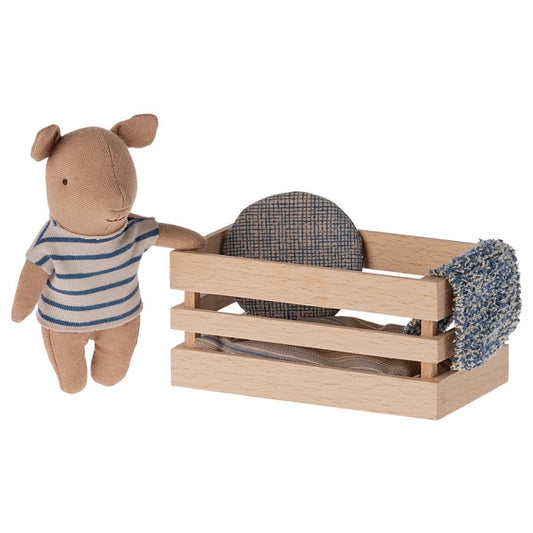 A mini Maileg pig in a wooden crate complete with bedding and a blue and white stripey outfit