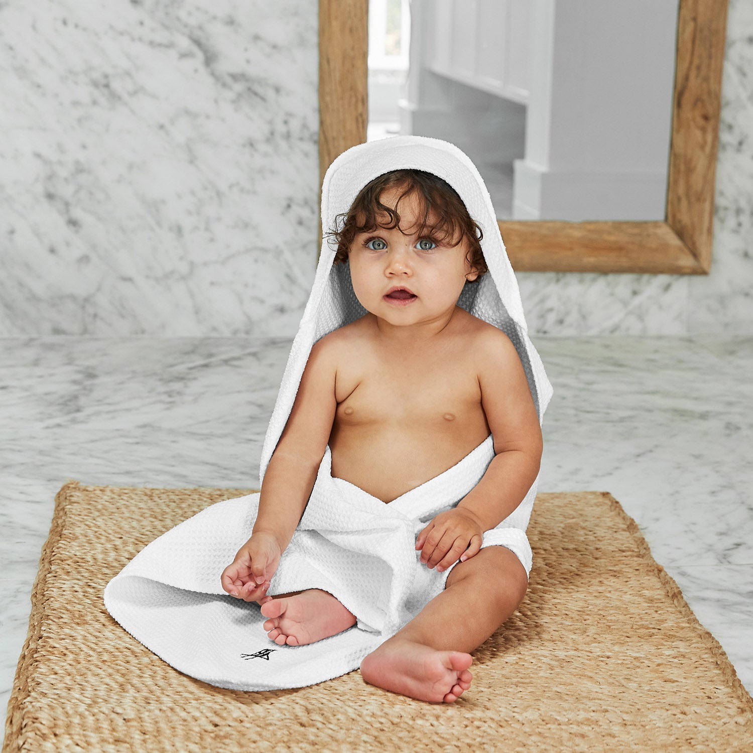 baby in a white hooded baby towel from Dock and Bay