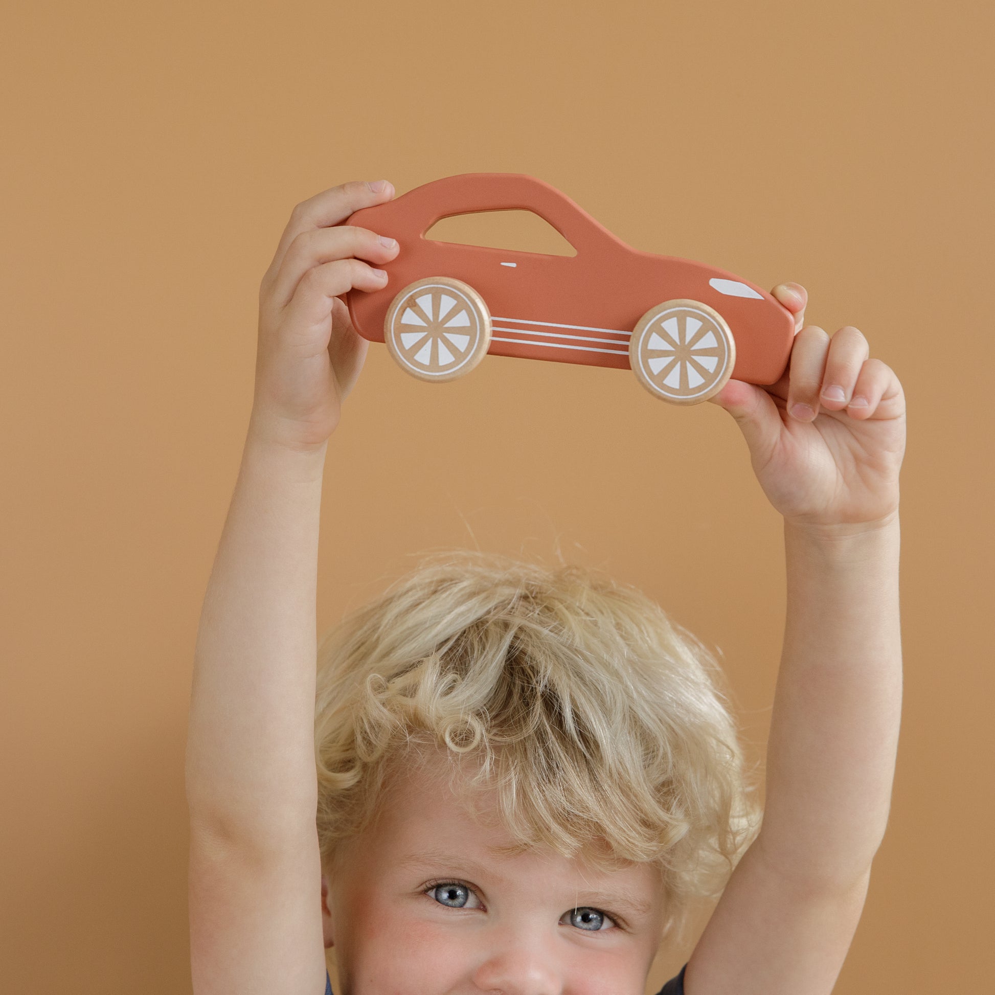 child holding up a Little Dutch wooden red sports car