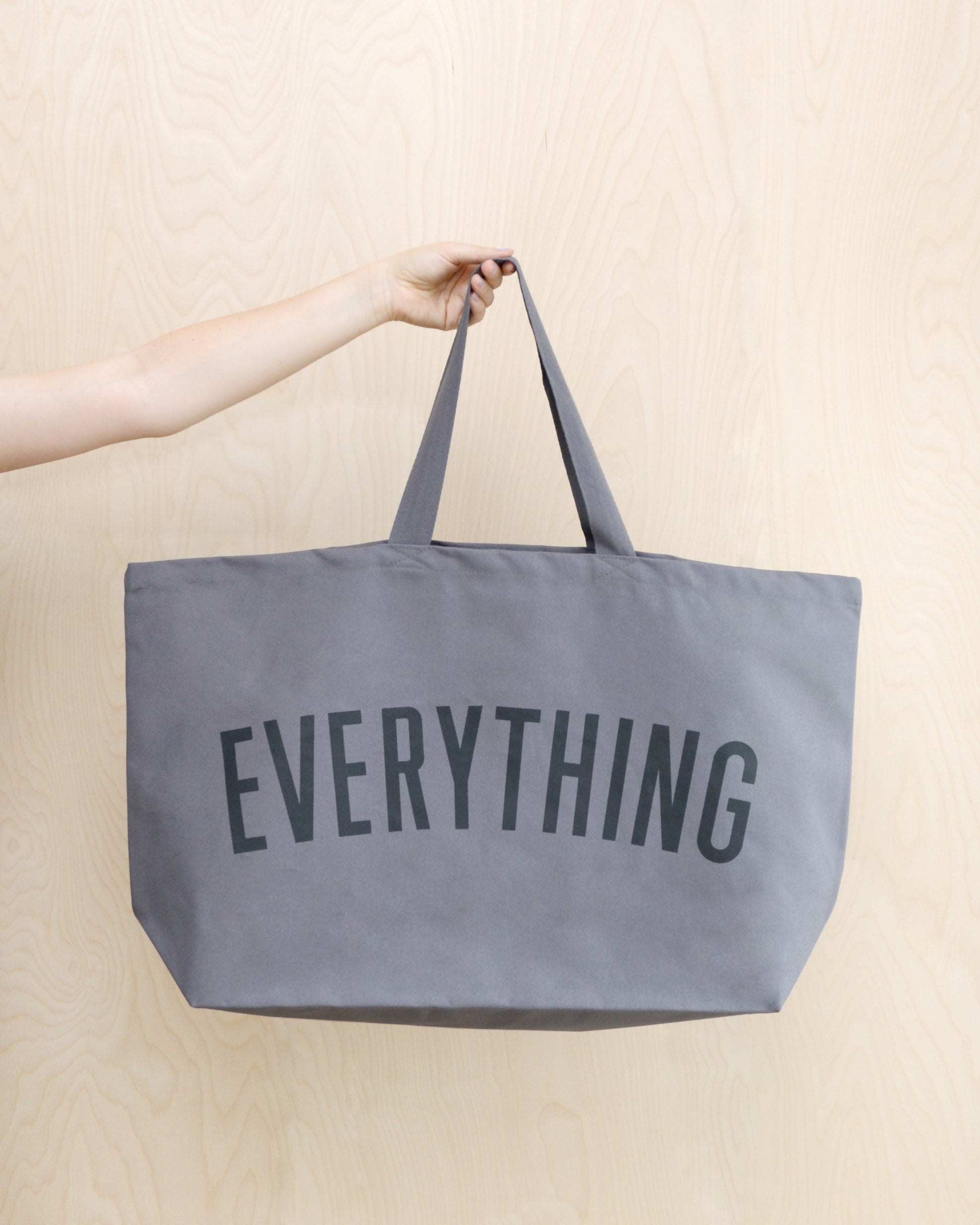 large grey tote bag screenprinted with the word everything in charcoal grey