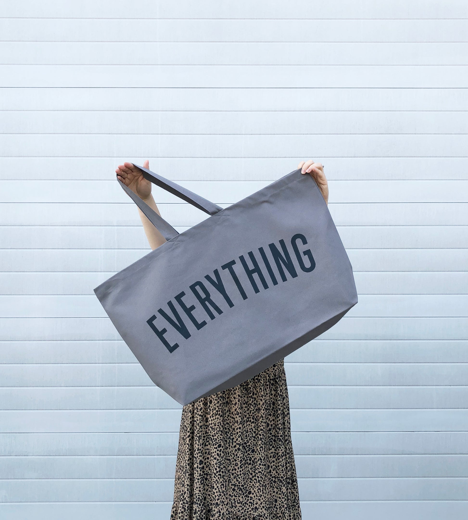 person holding large grey tote bag screenprinted with the word everything in charcoal grey